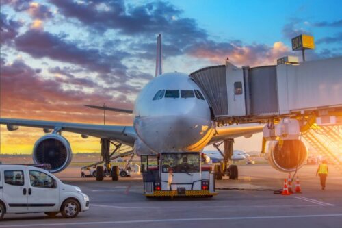 Commercial Airplane Parked at Airport Gate With Jet Bridge and Ground Service Vehicles